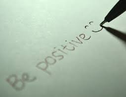 Foto que sale una papel y un lápiz escribiendo Be positive. 
