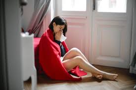 Mujer sentada en el suelo con una manta roja por encima sonándose la nariz, con un semblante estado anímico deprimido y como sin ganas de nada. Como tratar la ansiedad, como tratar la depresión, tratar el estrés, alimentación sana, relación del nervio vago con la ansiedad, como cuidar el nervio vago, técnicas de relajación.