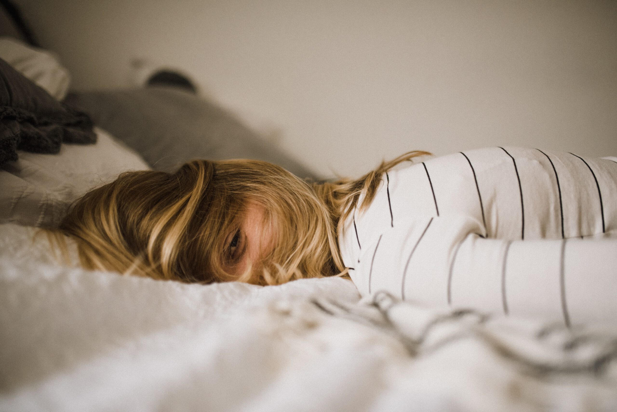 Mujer acostada sobre la cama con los ojos abiertos sin poder dormir. Como tratar la ansiedad, como tratar la depresión, tratar el estrés, alimentación sana, relación del nervio vago con la ansiedad, como cuidar el nervio vago, técnicas de relajación.